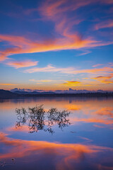 Fototapeta premium Landscape of mountains and lake at sunset and clouds reflected in the water.