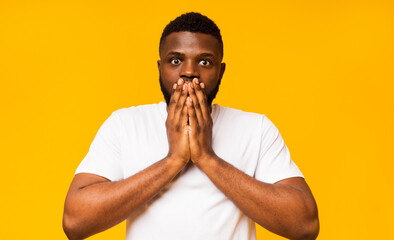 It can't be real. Shocked black guy shut his mouth in amazement, yellow background