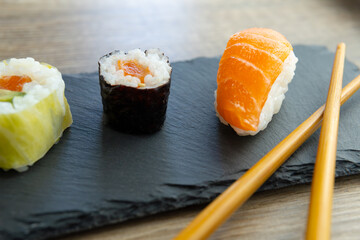 close-up photo of a sushi plate with Salmon avocado eel nigiri maki and wooden chopsticks on a gourmet restaurant table. © PHOTOSORIA