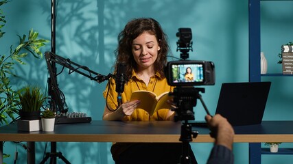 Excited content creator films video review of book, browsing through pages, impressed by story....