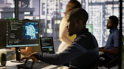 Admin creating AI machine learning models that can process and analyze data to improve decision making processes, looking at PC. Man programming in office using artificial intelligence tech, camera A