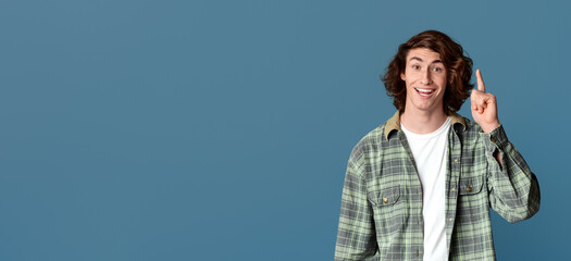 Happy young guy having brilliant idea, gesturing EUREKA on turquoise background
