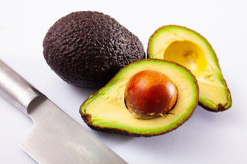 Fresh avocadoes and kitchen knife over white background.