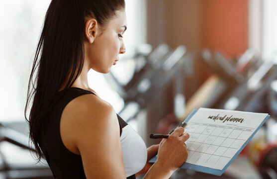 Personal trainer with clipboard making workout plan in sports club