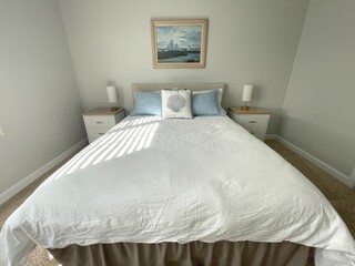 A clean, small bedroom with both a made bed and two night tables.