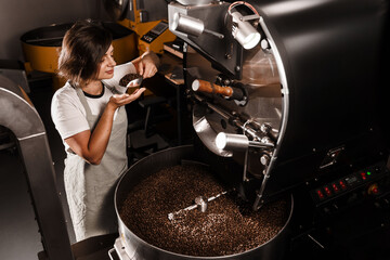 Roasted coffee beans in roasting machine in the production. High quality coffee beans manufacturing. Handful of fried coffee grains.