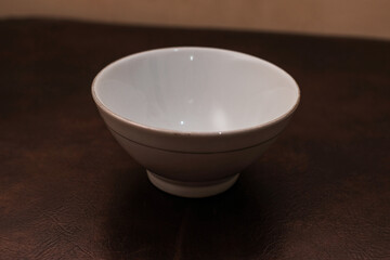Overhead view of a mini white ceramic bowl on a brown background, Top view of a white ceramic mixing bowl, Flat lay of ceramic batter bowl