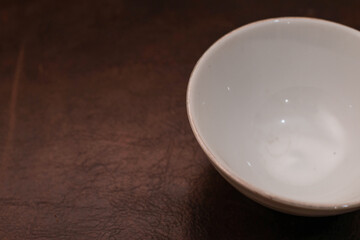 Overhead view of a mini white ceramic bowl on a brown background, Top view of a white ceramic mixing bowl, Flat lay of ceramic batter bowl
