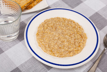 Appetizing milk oatmeal porridge served on plate for breakfast