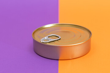 Unopened Tin Can on Split Orange and Violet Background. Canned Food. Aluminum Can for Safe and Long Term Storage of Food. Steel Sealed Food Storage Container