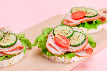 Light Breakfast. Quick and Healthy Sandwiches. Rice Cakes with Ham, Tomato, Fresh Cucumber and Green Salad on Wooden Cutting Board