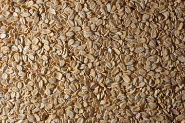 Uncooked Oat Flakes background - Top View, Flat Lay. Scattered Dry and Raw Oat Flakes. Healthy Breakfast and Diet Eating Ingredients