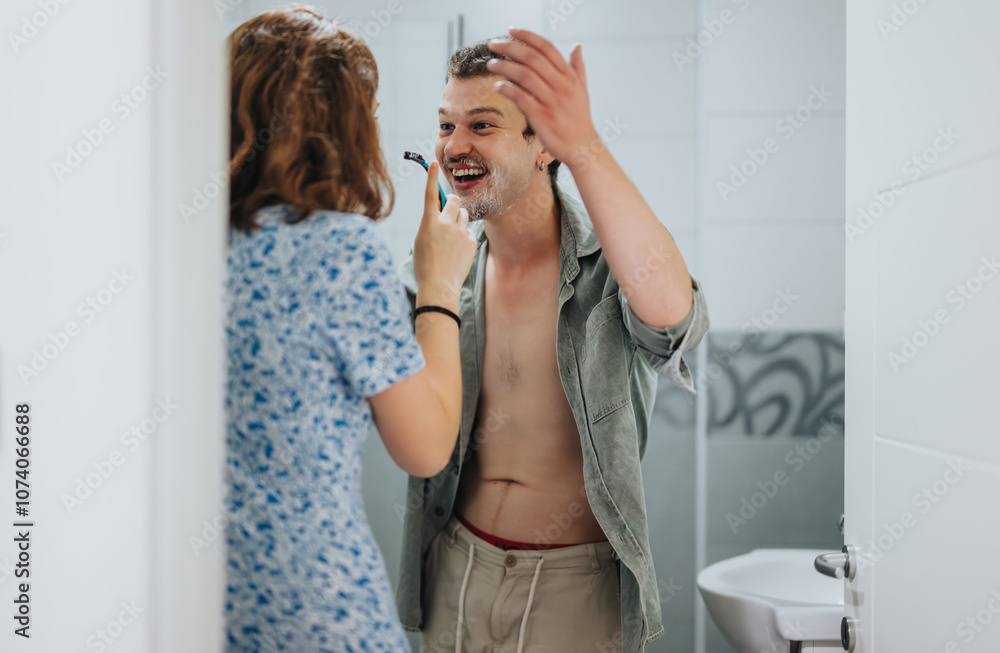 Poster A couple shares a playful moment while preparing for a night out. The cheerful interaction captures joy and companionship in a bathroom setting.