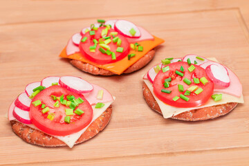 Crispy Cracker Sandwiches with Tomato, Sausage, Cheese, Green Onions and Radish on Cutting Board. Easy Breakfast. Quick and Healthy Sandwiches. Crispbread with Tasty Filling. Healthy Dietary Snack