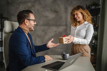 Female colleague give present to her male colleague in the office