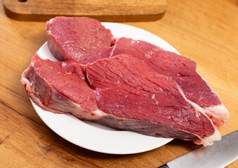 Raw beef fillet on the kitchen table along with other ingredients for making a delicious lunch or dinner