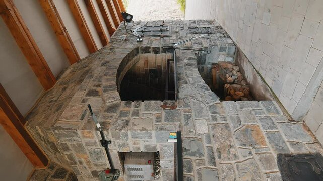 Stone barbecue firewood, open brick oven for cooking kebabs and other dishes on fire indoors in backyard. Restaurant kitchen, pizza oven and bar-b-q grill. Cooking food. Interior modern construction