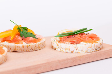 Rice Cake Sandwiches with Fresh Salmon, Cucumber, Yellow Paprika and Greens on Wooden Cutting Board. Diet Food. Quick and Healthy Sandwiches. Crispbread with Fresh Fillings. Healthy Dietary Snacks