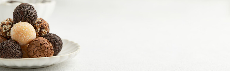 Typical Brazilian sweet brigadeiro. A heap of assorted flavors of candies on a white table