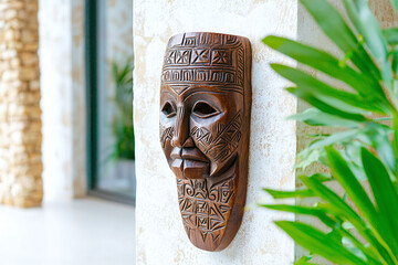 A carved Inuit mask hanging on a wall, with intricate designs.