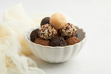 Typical Brazilian sweet brigadeiro. A heap of assorted flavors of candies on a white table