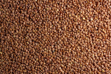 Dry Uncooked Brown Buckwheat Groats Background - Top View, Flat Lay. Raw Large Buckwheat Grains. Russian, Ukrainian and Belarusian Culture