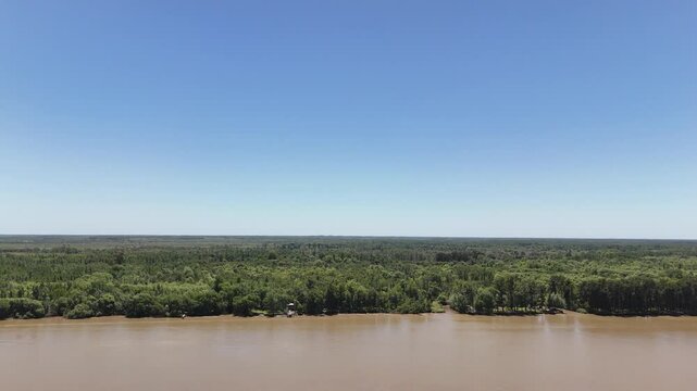 r&iacute;o paran&aacute; con &aacute;rboles en la costa y barcos navegando, atardecer