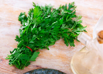Bunch of fresh green parsley twigs on wooden kitchen table.