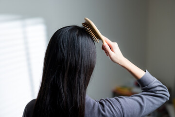 Fototapeta premium Woman Brushing Long Black Hair at Home
