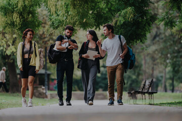 Obraz premium A group of students and their professor take a relaxing walk in a park, enjoying ice cream together after classes. They engage in friendly conversation under the lush green trees.