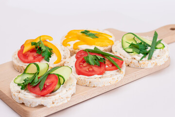 Different Vegan Rice Cake Sandwiches with Fresh Tomato, Yellow Paprika and Greens on Wooden Cutting Board. Vegetarian Diet Food. Quick and Healthy Sandwiches. Crispbread with Fresh Fillings
