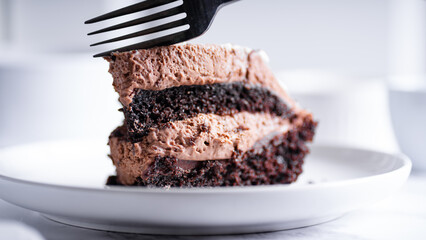 Chocolate cake with fork on white plate. Selective focus.
