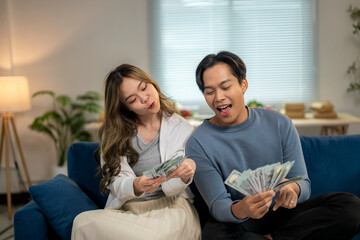 A man and a woman are sitting on a couch, both holding money