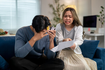 A man and woman are sitting on a couch, with the woman holding a piece of paper
