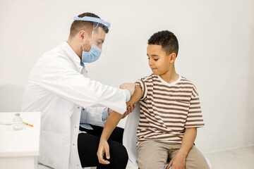 Obraz premium Male doctor doing a vaccination to a multiracional boy