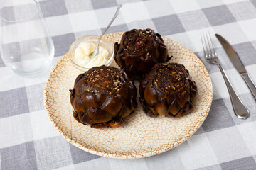 Top view of vegetarian appetizer of chargrilled artichokes served on white plate