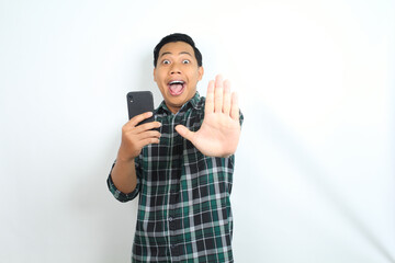 stop, asian man holding smartphone looks surprised isolated on white background, wearing casual green shirt