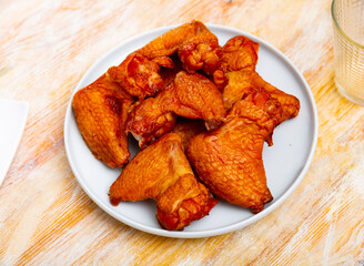 Delicious fried chicken wings dished up in a service plate on the laid restaurant table