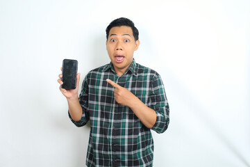 cheerful and excited asian man pointing smartphone screen with surprised face isolated on white background