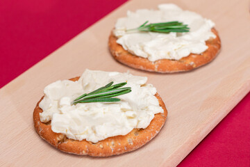 Crispy Cracker Sandwich with Cream Cheese and Rosemary on Wooden Cooking Board on Magenta Background