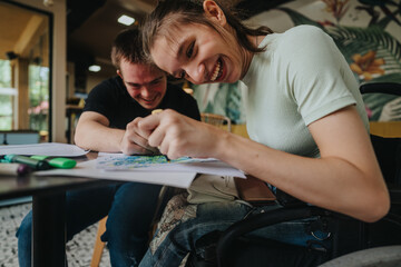 A male with Down syndrome and a girl in a wheelchair joyfully drawing and painting together,...