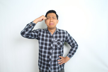 sad asian man crying and rubbing his eyes isolated on white background, male wearing plaid shirt