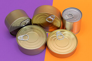 A Group of Stacked Tin Cans with Blank Edges on Split Orange and Violet Background. Canned Food....