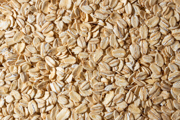 Uncooked Oat Flakes background - Top View, Flat Lay. Scattered Dry and Raw Oat Flakes. Healthy Breakfast and Diet Eating Ingredients