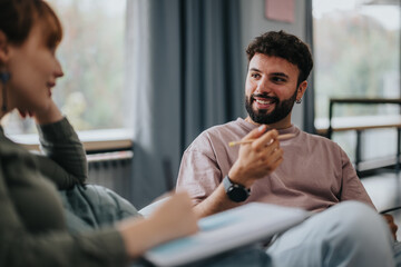 A young male professor having a thoughtful discussion with his students. The atmosphere is relaxed,...