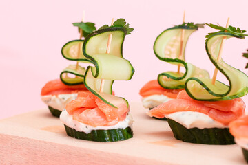 Canapes without Bread with Fresh Salmon, Cucumber and Cream Cheese on Wooden Cutting Board. Easy...