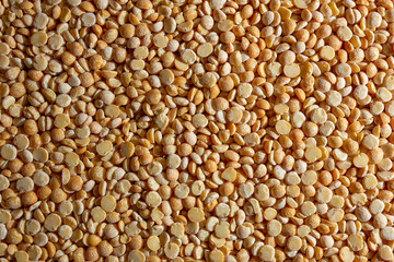Uncooked Polished Split Peas Background. A Culinary Canvas of Dry Yellow Peas, Creating a Lively and Textured Background for Gourmet Cooking. Scattered Raw Polished Peas. Healthy Eating Ingredients