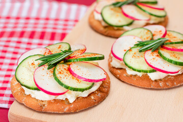 Light Breakfast or Diet Eating - Crispy Cracker Sandwich with Cream Cheese, Fresh Cucumber and Radish on Wooden Cooking Board on Magenta Background