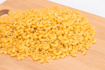 A Heap of Uncooked Chifferi Rigati Pasta on Wooden Kitchen Board. Fat and Unhealthy Food. Classic...