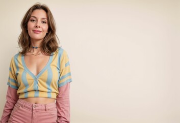 Obraz premium A woman with fair skin and shoulder-length light brown hair, styled in loose waves. She is wearing a pastel-colored, short-sleeve, V-neck top with yellow and blue stripes.